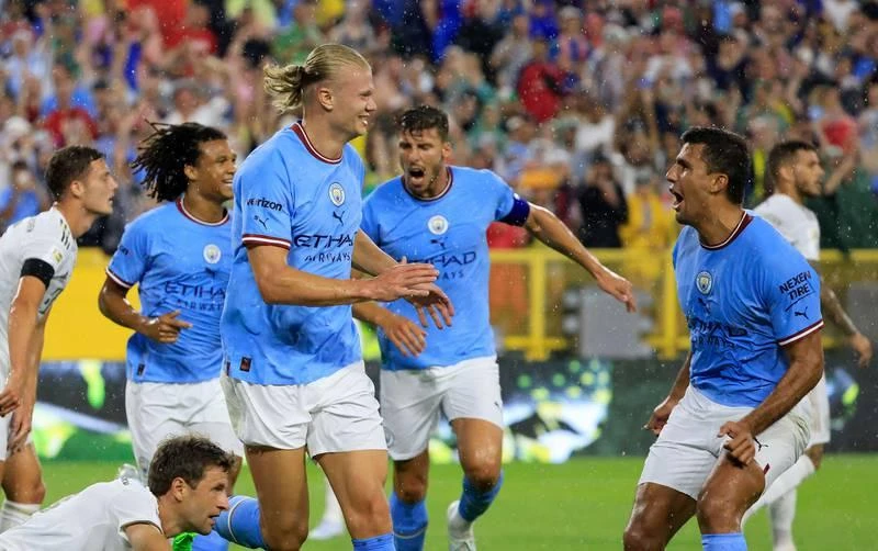 Để có được tay săn bàn người Na Uy này, Man. City bỏ ra 55 triệu bảng để có được. Grealish (áo xanh) của Man. City đối đầu với Thomas Muller. Haaland có nguồn sức khỏe và sức bật được đánh giá không thua gì Ronaldo. Julian Alvarez đi bóng qua Paul Wanner. Haaland chào khán giả trên sân Lambeau. Mùa hè này hàng loạt ông lớn châu Âu đến Mỹ để đá giao hữu với nhau. Grealish "không chiến" với hậu vệ Nianzou của Bayern. Các sân bóng Mỹ mùa hè này chào đón những Bayern, Man. City, Barcelona, Real Madrid... Haaland ghi bàn duy nhất trận giúp Man. City thắng "Hùm xám" 1-0. Nếu còn khoác áo Borussia Dortmund, Haaland và đồng đội dễ gì đánh bại "Hùm xám" Bayern.