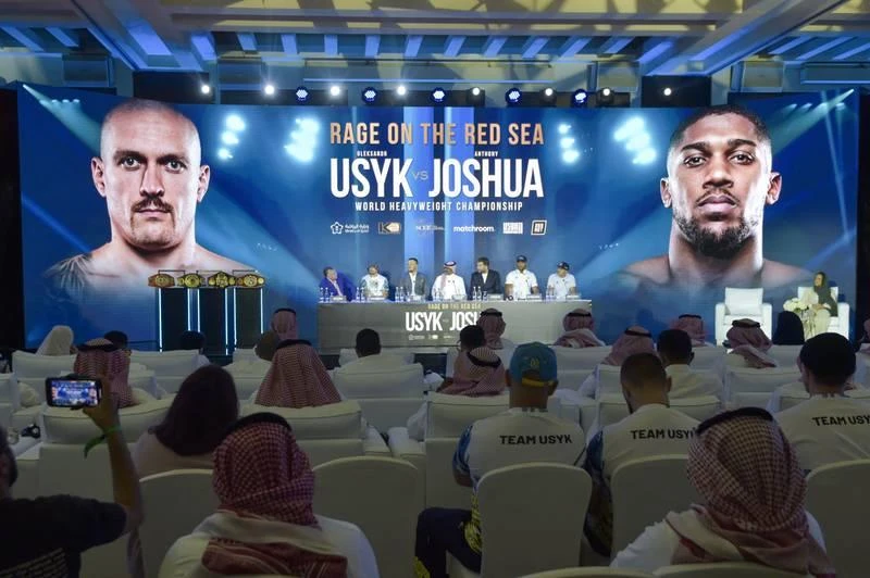Họp báo "chốt" trận tái đấu Joshua-Usuk vào ngày 20-8 tại Jeddah mang tựa đề "Cơn thịnh nộ của Hồng Hải". Joshua chuẩn bị rất chu đáo cho trận tái đấu này, thua nữa thì mất mặt quá. Các nhân viên đoàn làm phim chụp hình chung cùng Joshua. Usyk thấp hơn Joshua, nghĩa là cánh tay đòn ngắn hơn. ...Nhưng Usyk biết cách vô hiệu hóa lợi thế đối phương nhưng lại phát huy cú đấm gần đầy uy lực của mình. Công ty tổ chức giàu có của hoàng gia Saudi Arabia làm bộ phim quảng bá cho trận tái đấu ngày 20-8. Usyk còn mang cả tinh thần dân tộc Ukraine lên sàn đấu khi đất nước đang bị tàn phá bởi chiến tranh. Họp báo "chốt" trận tái đấu Joshua-Usuk vào ngày 20-8 tại Jeddah mang tựa đề "Cơn thịnh nộ của Hồng Hải". Joshua chuẩn bị rất chu đáo cho trận tái đấu này, thua nữa thì mất mặt quá. Các nhân viên đoàn làm phim chụp hình chung cùng Joshua. Usyk thấp hơn Joshua, nghĩa là cánh tay đòn ngắn hơn. ...Nhưng Usyk biết cách vô hiệu hóa lợi thế đối phương nhưng lại phát huy cú đấm gần đầy uy lực của mình. Công ty tổ chức giàu có của hoàng gia Saudi Arabia làm bộ phim quảng bá cho trận tái đấu ngày 20-8. Usyk còn mang cả tinh thần dân tộc Ukraine lên sàn đấu khi đất nước đang bị tàn phá bởi chiến tranh.