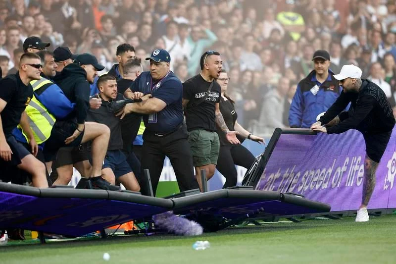 ... mà do ban tổ chức A-League đưa vòng chung kết của giải đấu này về Sydney ba mùa liên tiếp khiến fan Melbourne cay cú. Họ cáo buộc rằng, ban tổ chức A-League đã ăn tiền bẩn để đưa vòng chung kết A-League về Sydney ba mùa liên tiếp. Vụ lộn xộn này xuất phát từ một fan la lớn phản đối sau đó nhanh chóng lan rộng ra. Fan tràn xuống sân phá rồi đu người lên cả cầu môn.