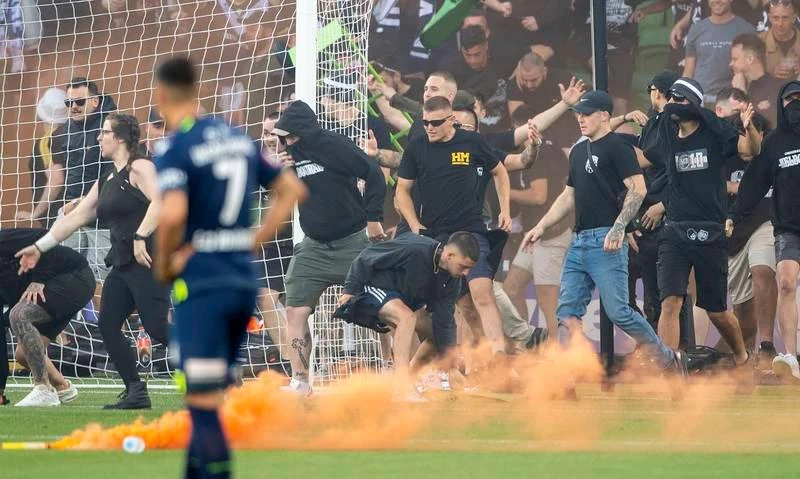 Bạo động không phải xuất phát từ tính chất căng thẳng trận derby Melbourne. ... mà do ban tổ chức A-League đưa vòng chung kết của giải đấu này về Sydney ba mùa liên tiếp khiến fan Melbourne cay cú. Họ cáo buộc rằng, ban tổ chức A-League đã ăn tiền bẩn để đưa vòng chung kết A-League về Sydney ba mùa liên tiếp. Vụ lộn xộn này xuất phát từ một fan la lớn phản đối sau đó nhanh chóng lan rộng ra. Fan tràn xuống sân phá rồi đu người lên cả cầu môn.