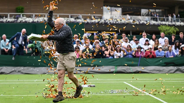 Một nhà hoạt động môi trường dùng giấy kim tuyến rải khắp mặt sân 18 ở Wimbledon để bày tỏ thái độ việc chính phủ Anh định bỏ dầu, thay vào đó là dùng than và khí đốt, đấy là vấn đề gây ô nhiễm môi trường. Ảnh: S.E Ngày thi đấu thứ ba của Wimbledon, những nhà hoạt động bảo vệ môi trường rải những mảnh kim tuyến lên mặt sân cùng lúc với trời mưa. Điều đó khiến trận đấu giữa Dimitrov và Shimabukuro phải hoãn, để nhân viên dọn dẹp những giấy kim tuyến cuốn vào cỏ rất khó gỡ. Ảnh: S.E Sang ngày thi đấu thứ năm cũng trên sân 18, những người hoạt động môi trường mặc áo phông với dòng chữ Just Stop Oil tiếp tục rải giấy kim tuyến lên mặt sân, lúc đó đang diễn ra trận đấu Katie Boulter và Daria Saville khiến trận đấu hoãn. Ảnh: S.E Những người vào sân quậy phá bị lực lượng chức năng trong sân bắt giữ và kéo ra khỏi sân. Ảnh: S.E Những mảnh giấy kim tuyến cực mỏng dính vào cỏ rất tốn công "gỡ từng sợi". Ảnh: S.E Giá cả leo thang, lạm phát khiến tình hình xã hội căng thẳng, nay lại bỏ dầu dùng than và khí gas sẽ gây ô nhiễm môi trường, những người phản đối lập luận như thế. Ảnh: S.E