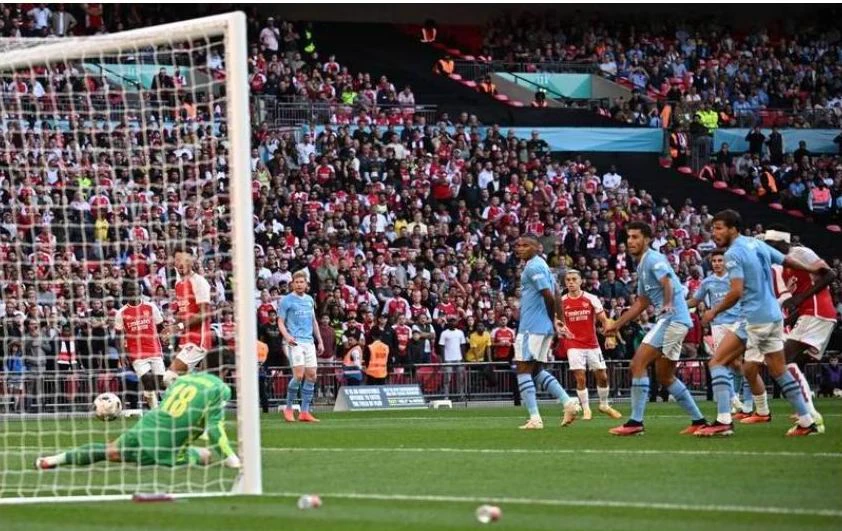 Giấc mơ "ăn sáu" của thầy trò HLV Pep Guardiola tan vỡ. Còn trận Siêu cúp châu Âu, liệu Man. City sẽ đánh bại Sevilla của Tây Ban Nha? HLV Mikel Arteta mừng ra mặt với danh hiệu đầu mùa, sau mùa bóng bị ì lại ở giai đoạn nước rút khiến Man. City vượt lên ẵm danh hiệu ngoại hạng. Ảnh: Reuters Erling Haaland thừa nhận rằng anh bị áp lực cực lớn ở những trận chung kết vì đối phương "chăm sóc" quá kỹ. Ảnh: AP Dẫu sao cũng là một danh hiệu "có hậu" với "Pháo thủ thành London". Ảnh: AFP Hy vọng mùa bóng mới Arsenal sẽ tiếp tục là thế lực đáng gờm của Man. City. Ảnh: AFP HLV Pep Guardiola không tin vào mắt mình ngay sau bàn san bằng 1-1 của Leandro phút 90+11 và rồi Man. City thua cuộc ở "loạt đấu súng". Ảnh: AFP Lâu lắm rồi Arsenal mới có danh hiệu trở lại. Ảnh: AFP