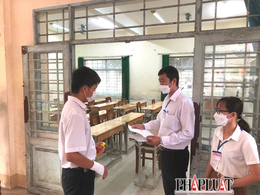 Cán bộ coi thi kiểm tra giấy báo thi của Hùng trước khi vào phòng. Ảnh: NHẪN NAM Cán bộ coi thi kiểm tra giấy báo thi của Hùng trước khi vào phòng. Ảnh: NHẪN NAM