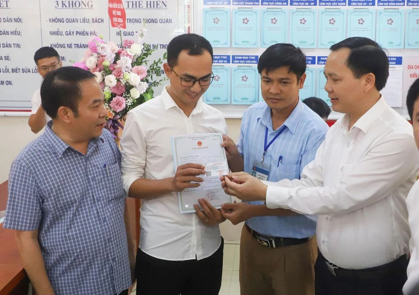 Ông Chu Mạnh Sinh (bìa phải), Phó Tổng giám đốc BHXH Việt Nam, trao thẻ BHYT, giấy khai sinh cho con anh Đinh Tiến Hoàng. (Ảnh: BHXH Việt Nam cung cấp)