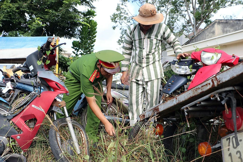 Thiếu tá Cao Minh Tân hướng dẫn nghi can, phạm nhân cắt cỏ khu vực nhà để xe vi phạm của công an huyện. Ảnh: VÕ TÙNG Thiếu tá Cao Minh Tân hướng dẫn nghi can, phạm nhân cắt cỏ khu vực nhà để xe vi phạm của công an huyện. Ảnh: VÕ TÙNG