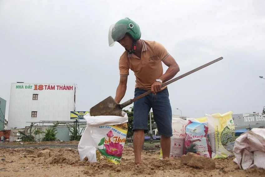 Một người dân xúc đất cát mang về đặt trên mái nhà chống bão. Ảnh: NGÔ QUANG Một người dân xúc đất cát mang về đặt trên mái nhà chống bão. Ảnh: NGÔ QUANG