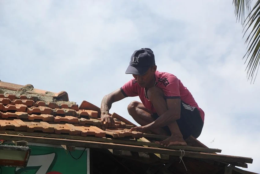 Chồng chị Quế đang sửa lại mái nhà sau bão. Ảnh: NGÔ QUANG