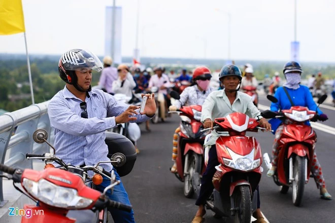 Người dân lần đầu được ngắm dòng sông Vàm Cỏ từ trên cao. Nhiều người dùng điện thoại ghi lại những hình ảnh này. Con đưa di ảnh ba mẹ ngắm cầu Mỹ Lợi ngày thông xe