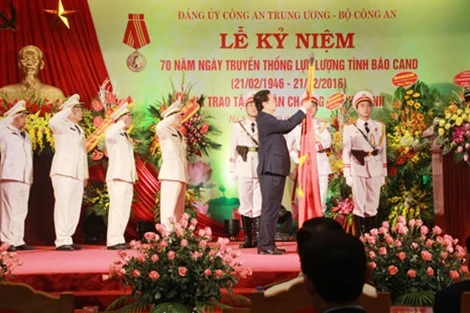 Thủ tướng Chính phủ Nguyễn Tấn Dũng gắn huân chương Hồ Chí Minh lên cờ truyền thống của lực lượng tình báo CAND. Ảnh: Công an Nhân dân