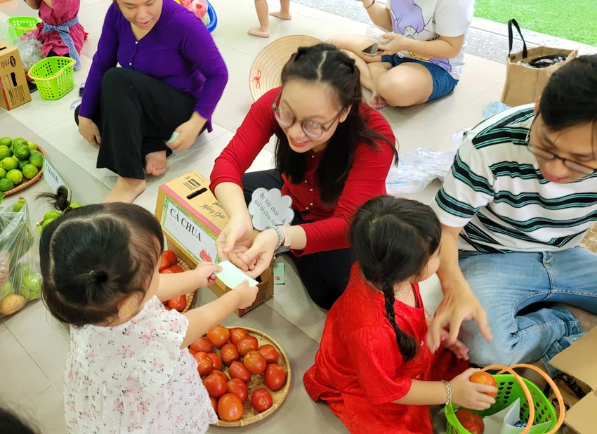 Bé gái lễ phép đưa phiếu bằng hai tay, bạn bên cạnh đang chọn mua cà chua. Bé gái lễ phép đưa phiếu bằng hai tay, bạn bên cạnh đang chọn mua cà chua.