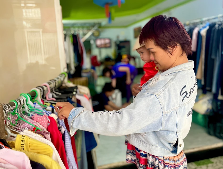 Chị Lê Thị Tuyết Phượng bế con gái nhỏ đến lựa chọn quần áo. Ảnh: TÚ NGÂN Chị Lê Thị Tuyết Phượng bế con gái nhỏ đến lựa chọn quần áo. Ảnh: TÚ NGÂN