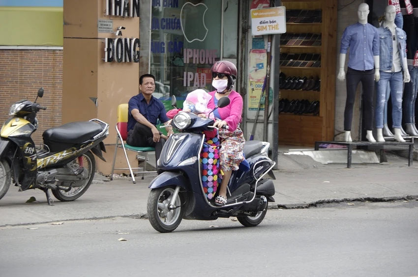 Một em bé được mẹ trùm kín từ đầu tới chân để tránh gió lạnh.