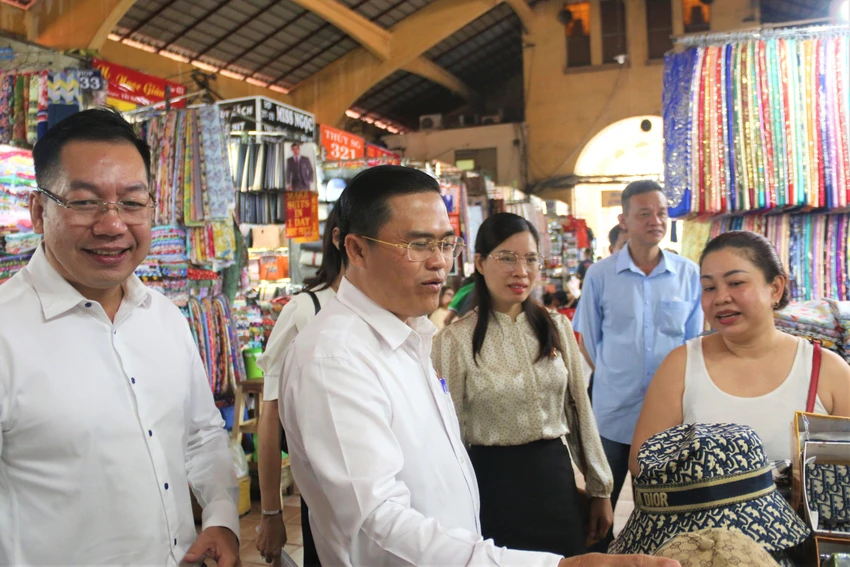 Ông Ngô Văn Hà (bên trái) cùng đoàn khảo sát đến thăm hỏi tiểu thương ở chợ. Ảnh: THẢO PHƯƠNG