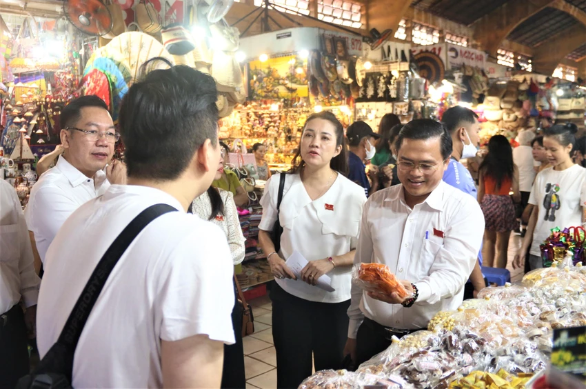 Ông Cao Thanh Bình (bìa phải) hỏi thăm tình hình buôn bán bánh mứt của anh Tín. Ảnh: THẢO PHƯƠNG