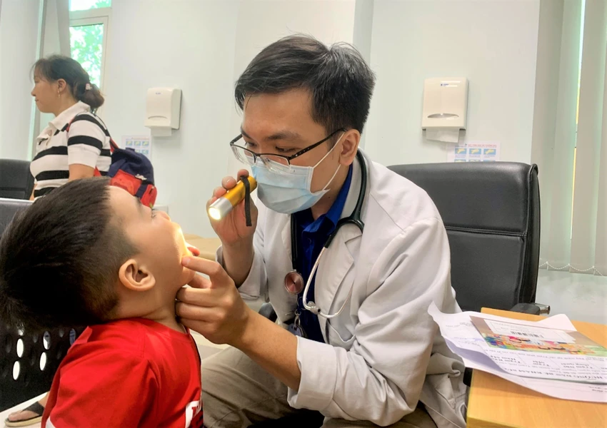 Bác sĩ khám tai mũi họng cho con chị Diễm. Ảnh: THẢO PHƯƠNG