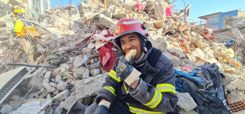 Một thành viên trong đoàn cứu hộ của Việt Nam ăn vội bánh mì tại hiện trường tòa nhà đổ nát. Ảnh: Cục Cảnh sát PCCC&amp;CNCH