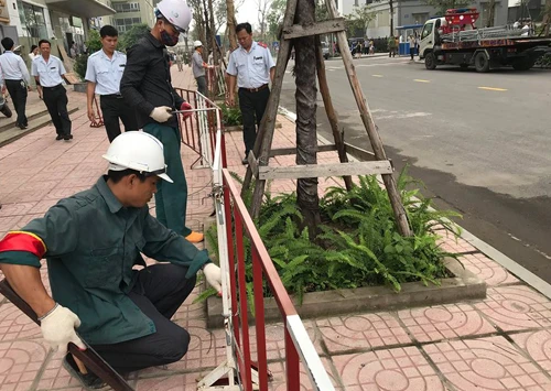 Lực lượng chức năng phá dỡ rào chắn bằng sắtdựng trên vỉa hè chung cư Vinaconex 7. Ảnh: Gia Chính.
