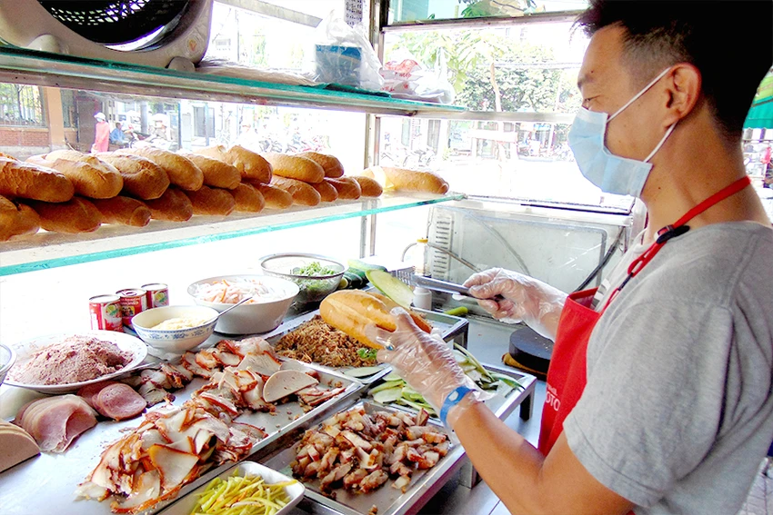 Một người bán bánh mì ở TP.HCM luôn đeo khẩu trang, mang găng tay. Ảnh: TRẦN NGỌC Một người bán bánh mì ở TP.HCM luôn đeo khẩu trang, mang găng tay. Ảnh: TRẦN NGỌC