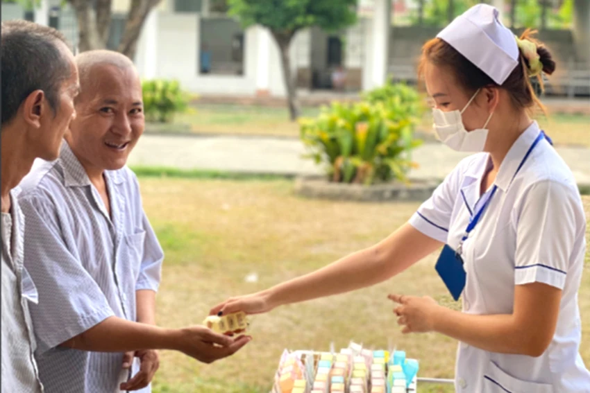 Bệnh nhân tâm thần đang nhận thuốc từ điều dưỡng Nguyễn Thị Bích Ngọc. Ảnh: TRẦN NGỌC