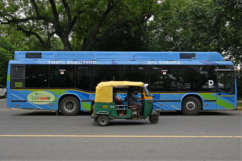 Một chiếc xe lam chạy ngang qua chiếc xe buýt điện ở New Delhi (Ấn Độ). Ảnh: AFP