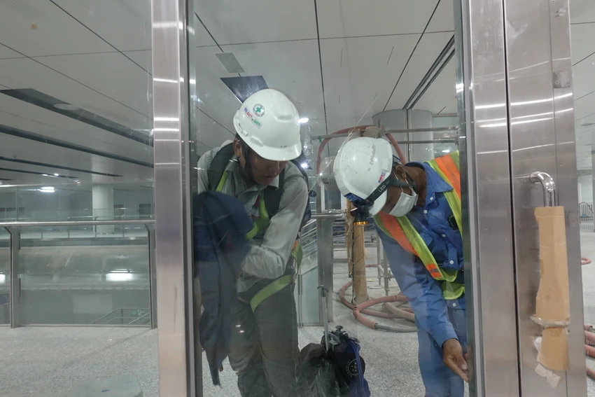 Công nhân lắp đặt cửa kính, phòng soát vé ở tầng B1.