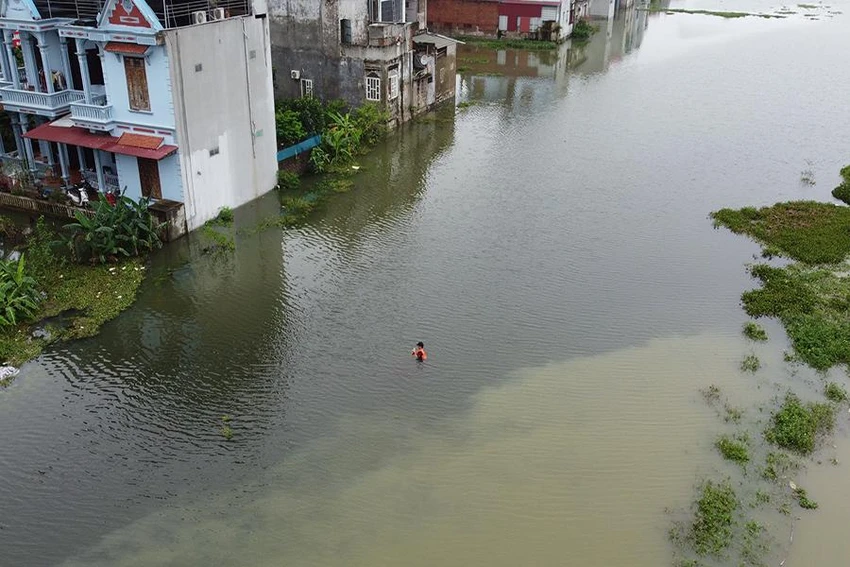 Một người đàn ông ở xã Minh Tâm băng qua đường để trở về nhà khi lũ dâng cao. Ảnh: ĐẶNG TRUNG Một người đàn ông ở xã Minh Tâm băng qua đường để trở về nhà khi lũ dâng cao. Ảnh: ĐẶNG TRUNG