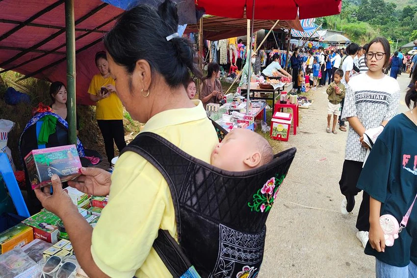 Một bé trai ngủ quên trên lưng mẹ trong hành trình xuống chợ cùng mẹ.