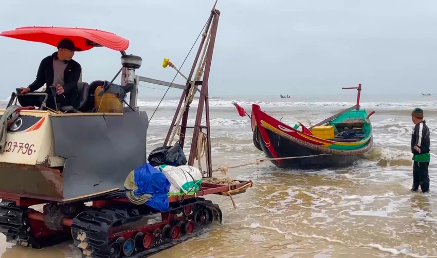 Ngư dân kéo tàu vào bờ. Ảnh: BT Ngư dân kéo tàu vào bờ. Ảnh: BT