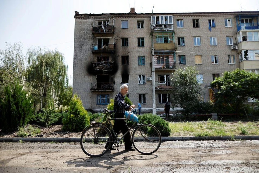 Người dân đi qua tòa nhà bị hư hại do pháo kích ở tỉnh Donetsk hôm 28-8. Ảnh: REUTERS Người dân đi qua tòa nhà bị hư hại do pháo kích ở tỉnh Donetsk hôm 28-8. Ảnh: REUTERS