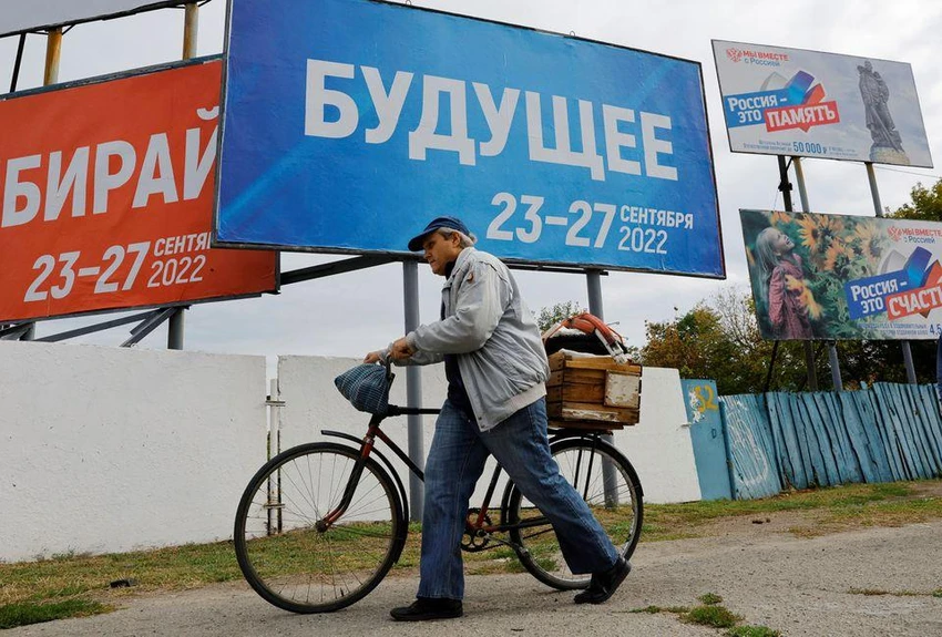 Người dân đi qua bảng hiệu về việc trưng cầu dân ý ở TP Melitopol. tỉnh Zaporizhia. Ảnh: REUTERS Người dân đi qua bảng hiệu về việc trưng cầu dân ý ở TP Melitopol. tỉnh Zaporizhia. Ảnh: REUTERS