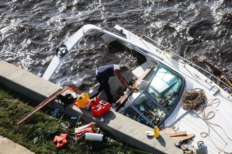 Một người đàn ông đứng trên chiếc thuyền bị đắm ở thành phố Punta Gorda, quận Charlotte. Ảnh: REUTERS