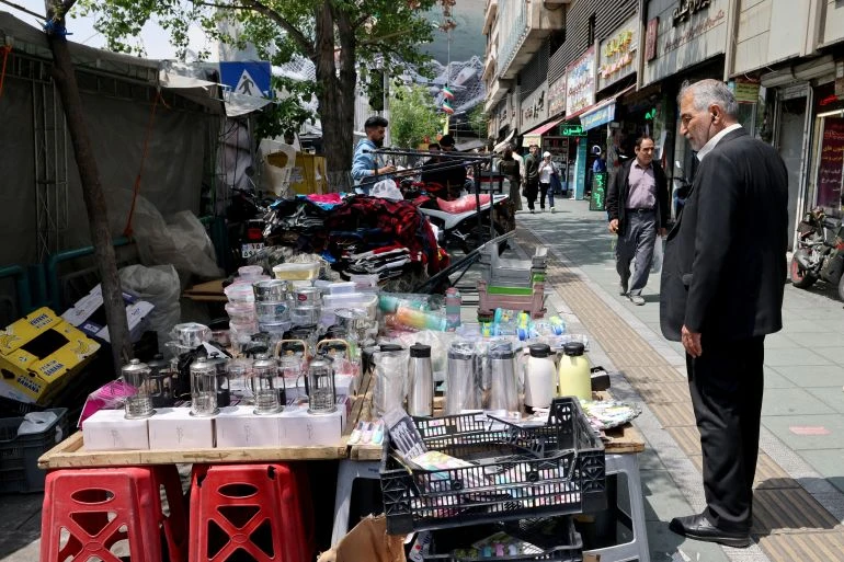 Một người Iran đang mua hàng tại một quầy bán dạo dựng trên vỉa hè ở trung tâm Tehran ngày 22-4. Ảnh: Atta Kenare/AFP