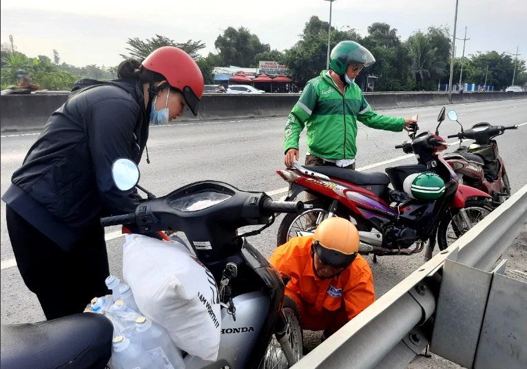 Người đàn ông áo vàng đang thay ruột xe mới cho người phụ nữ. Ảnh: TRẦN NGỌC Người đàn ông áo vàng đang thay ruột xe mới cho người phụ nữ. Ảnh: TRẦN NGỌC