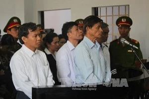 Bị cáo Vũ Việt Hùng (áo xanh bên phải) trước vành móng ngựa. (Ảnh: K' Guih/TTXVN)