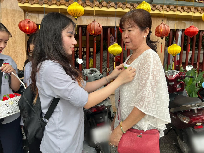 Bạn Hứa Ngọc Bích (20 tuổi), làm việc trong nhóm cài hoa hồng cho biết: "Chúng em cảm thấy vui vì được là người thực hiện công việc ý nghĩa này. Em hy vọng những cành hoa khi được cài lên ngực của mỗi chúng ta, sẽ gợi nhớ về bậc sinh thành và tình cảm thiêng liêng và sự hiếu thảo của con cái gửi đến cha mẹ". Ảnh: QUỐC HƯƠNG. Bạn Hứa Ngọc Bích (20 tuổi), làm việc trong nhóm cài hoa hồng cho biết: "Chúng em cảm thấy vui vì được là người thực hiện công việc ý nghĩa này. Em hy vọng những cành hoa khi được cài lên ngực của mỗi chúng ta, sẽ gợi nhớ về bậc sinh thành và tình cảm thiêng liêng và sự hiếu thảo của con cái gửi đến cha mẹ". Ảnh: QUỐC HƯƠNG.