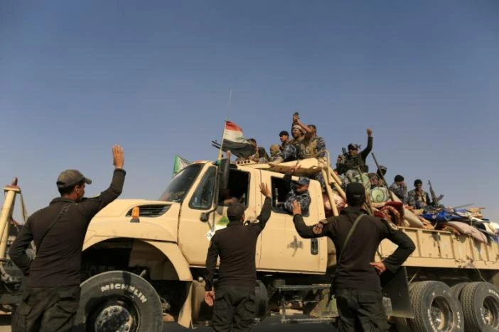 Lính đặc nhiệm Iraq vẫy tay với cảnh sát Iraq đang trên đường tiến về Mosul ngày 26-10. 