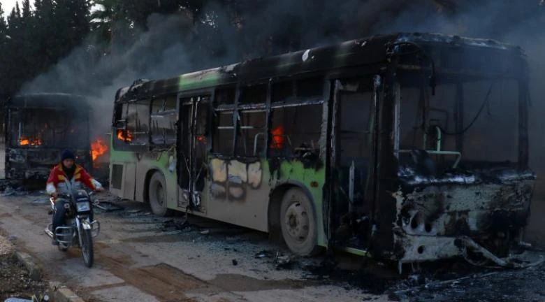 Xe buýt dùng chở người dân và phe nổi dậy sơ tán bị đốt gần tỉnh Idlib (Syria) ngày 18-12. Ảnh: REUTERS 
