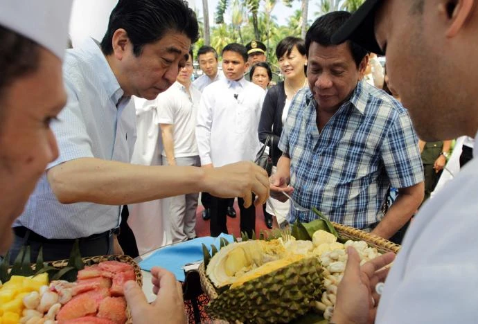 Tổng thống Duterte và Thủ tướng Abe (trái) ăn sầu riêng trong một sự kiện tại Davao (Philippines) ngày 13-1. Ảnh: REUTERS