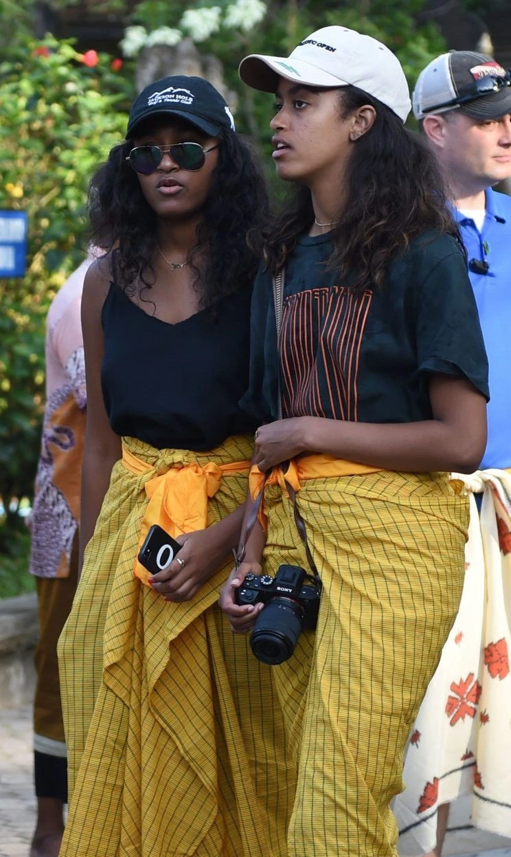 Hai con gái Malia và Sasha của nhà Obama mặc trang phục sarong vàng trước khi vào thăm đền Tirta ở Bali. Ảnh: GETTY IMAGES