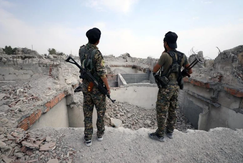 Các tay súng SDF bên cạnh một ngôi đền bị phá hủy ở Raqqa (Syria) ngày 16-9. Ảnh: REUTERS