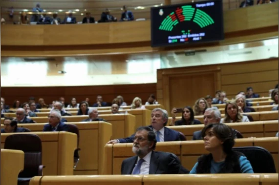 Thủ tướng Tây Ban Nha Mariano Rajoy (giữa) và Phó Thủ tướng nước này Soraya Saenz de Santamaria (phải) theo dõi kết quả bỏ phiếu của Thượng viện ngày 27-10 đồng ý biện pháp khẩn cấp tước quyền tự trị Catalonia. Ảnh: REUTERS