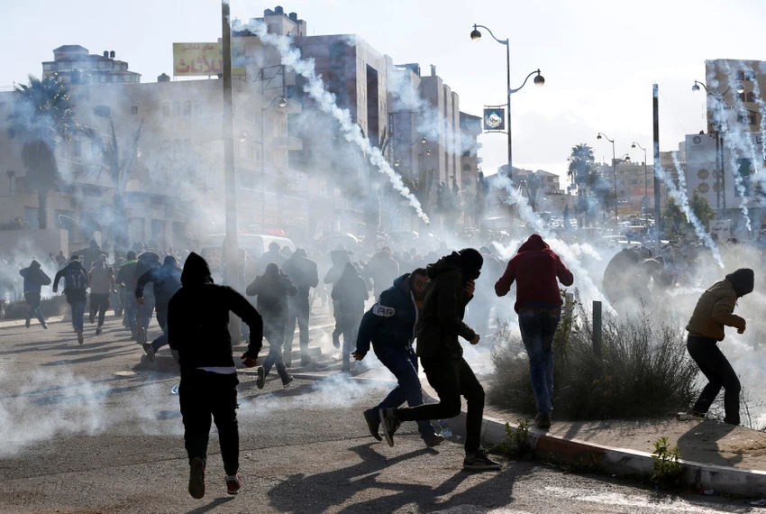 Binh sĩ Israel dùng hơi cay trấn áp người dân Palestine biểu tình gần khu định cư Do Thái Beit El, gần TP Ramallah ở Bờ Tây ngày 7-12, phản đối quyết định của Tổng thống Mỹ Donald Trump công nhận Jerusalem là thủ đô của Israel. Ảnh: REUTERS