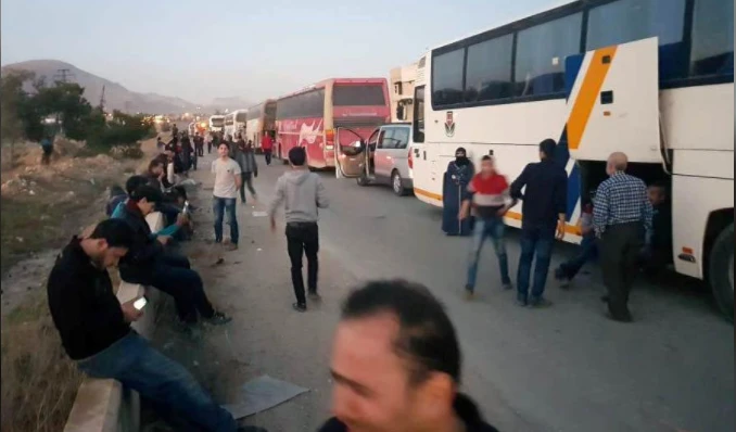 Người dân thị trấn Douma chờ lên xe rời Đông Ghouta, ngoại ô thủ đô Damacus (Syria) ngày 1-4. Ảnh: REUTERS