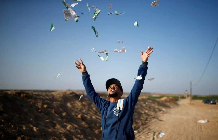 Một thanh niên Palestine xé tung các tờ rơi do không quân Israel thả xuống, đề nghị dân Palestine không tiếp cận biên giới với Israel, tại Dải Gaza ngày 14-5. Ảnh: REUTERS
