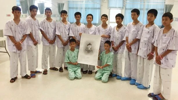 Đội bóng đá nhí chụp hình cùng di ảnh phác họa của thợ lặn Saman Kunan, cựu đặc nhiệm hải quân Thái Lan thiệt mạng vì thiếu ô xy trong quá trình lặn lắp đặt bình ô xy dọc hang động chuẩn bị cho công tác giải cứu. Ảnh: AP