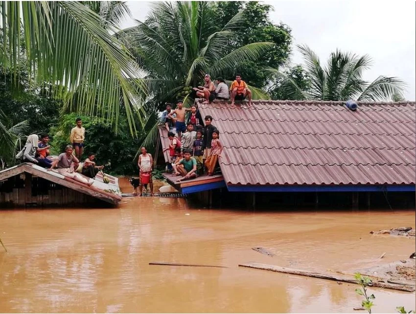 Người dân leo lên mái nhà tránh lụt sau khi con đập thuộc dự án thủy điện Xepian-Xe Nam Noy vỡ làm nước tràn ra, ngày 24-7. Ảnh: REUTERS