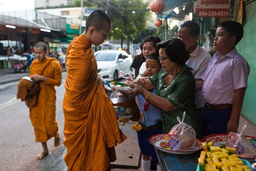 Một nhà sư trẻ đang nhận thức ăn từ các tín đồ Phật giáo. Ảnh: NEW YORK TIMES