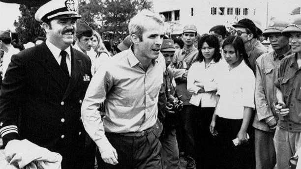Ông John McCain (giữa) được hộ tống đến sân bay ở Hà Nội ngày 14-3-1973 sau khi được thả. Ảnh: AP