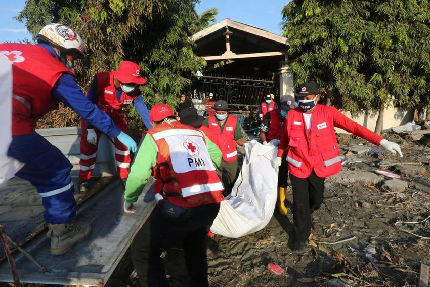 Nhân viên Hội Chữ thập đỏ Indonesia mang thi thể nạn nhân đi chôn tập thể tại Palu ngày 1-10. Ảnh: AP
