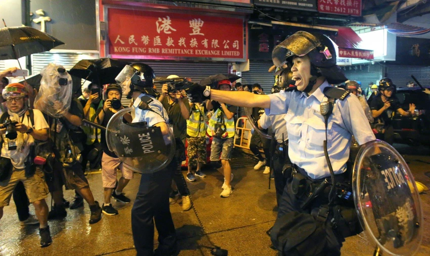 Cảnh sát chĩa súng vào người biểu tình, ngày 25-8. Ảnh: SCMP